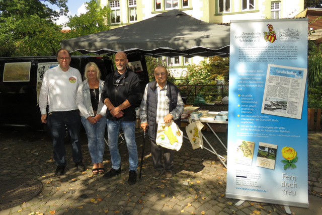 Der Vorsitzende der Zentralstelle, Daniel Spitzer, seine Frau Anke Maria und sein Onkel Reinhard Spitzer sowie der stellvertretende Vorsitzende Christian Drescher am Stand des Grafschafter Boten